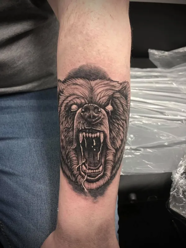 Front view of a roaring bear head tattoo on a forearm.