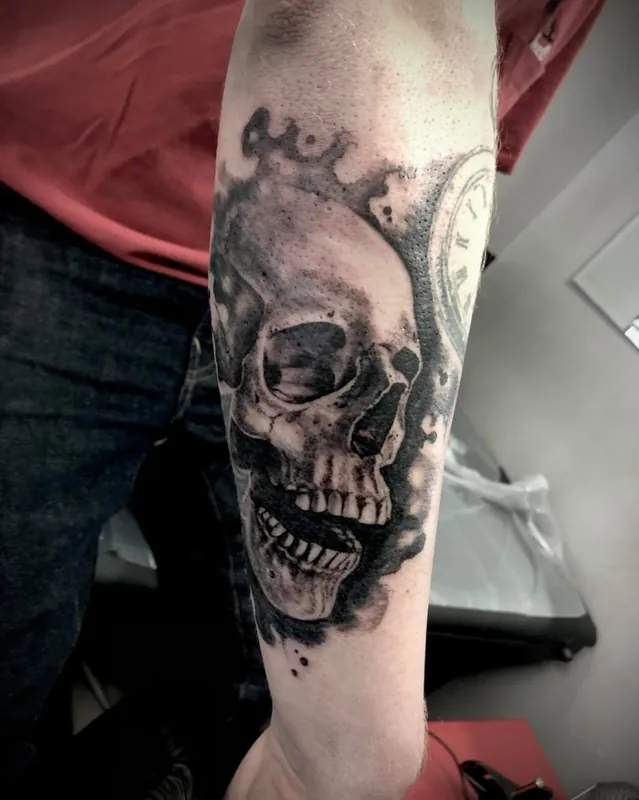 A shaded human skull tattoo on a forearm.