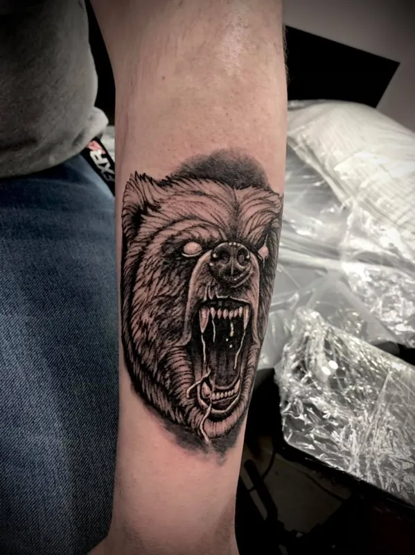 Angled view of a roaring bear head tattoo on a forearm.