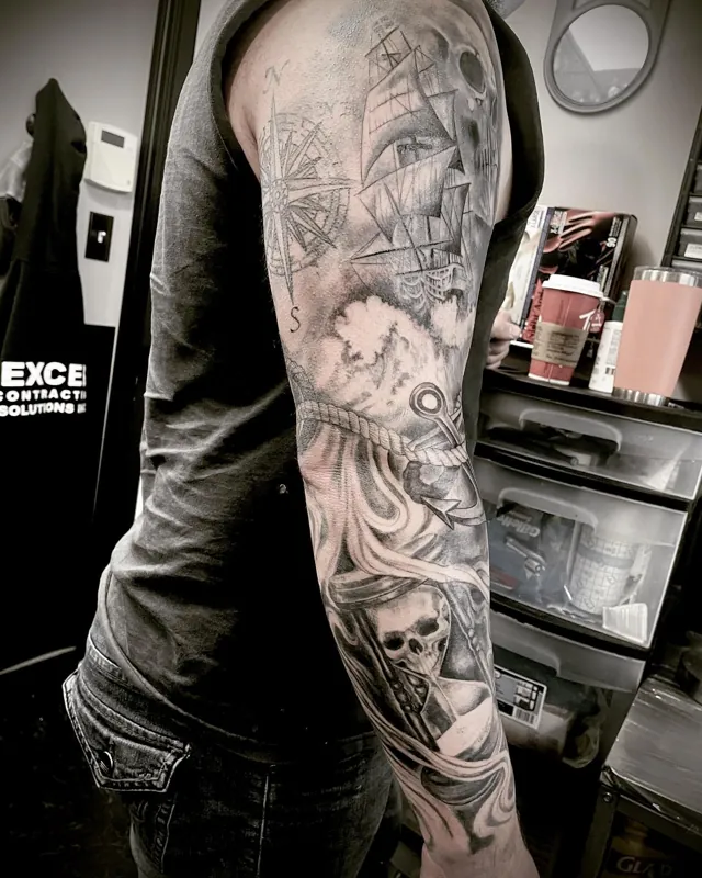 A black and grey arm sleeve with a sailing ship, skulls and curling tentacles.