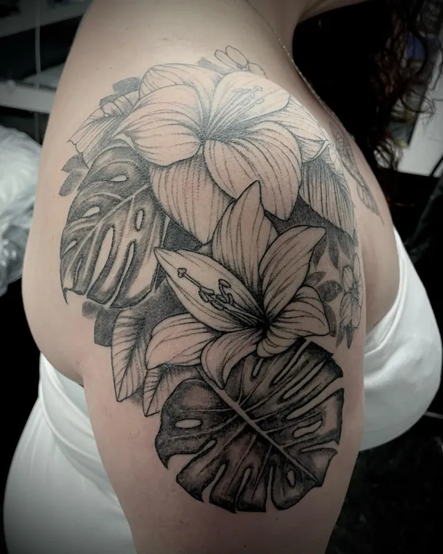 Tropical blossoms and split leaves tattooed across an upper arm.